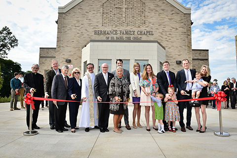 A group of people cut a ribbon at the dedication of the Hermance Family Chapel of St. Basil the Great.