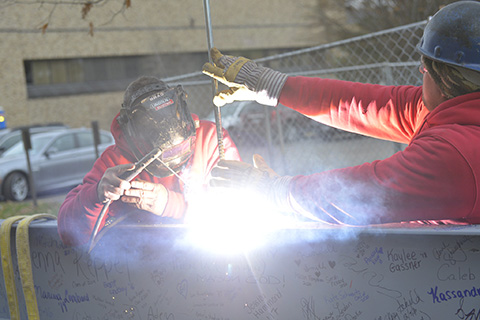 Welders preparing to install the final beam of the Hermance Family Chapel.