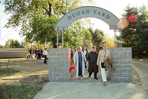 A group at the Dugan Yard Ribbon cutting walk under the archway.