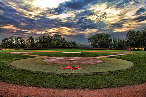 Landscape of Dugan Yard baseball field with bright clouds in the sky at sunset.