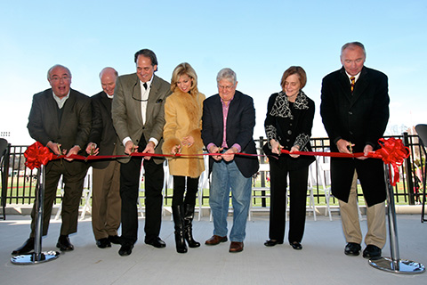 A group of people use scissors to cut a ribbon at the Polisseni Track and Field Complex.
