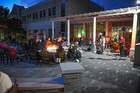 Students gather to hear live music outdoors in the evening at the Terrace at Tepas Commons.