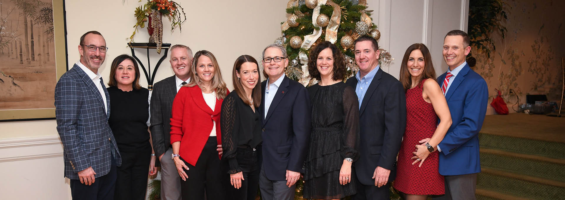 Group of men and women standing in front of a Christmas tree