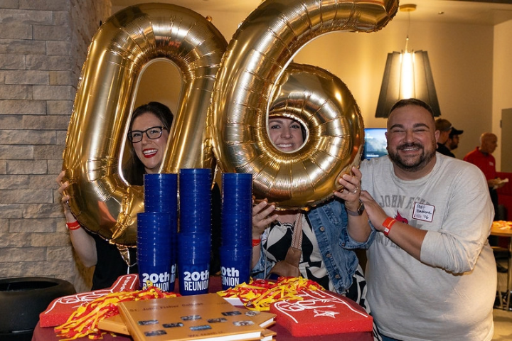 Three alumni with balloons that read 06
