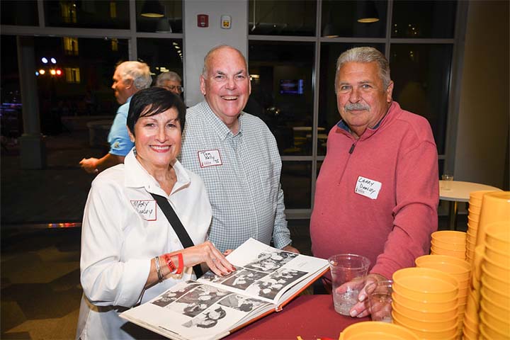 Three people together sharing their old yearbook photo