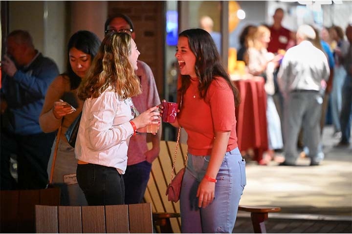 Two friends laugh together at an outdoor event