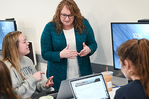 A professor talking with a student over a laptop.