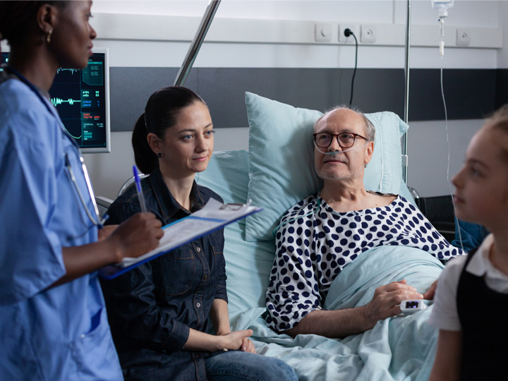 A man in a hospital bed accompanied by a health care provider and family members.