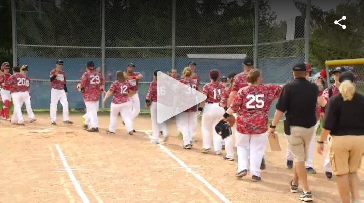 A group of Special Olympics Athletes gathers on a baseball field.