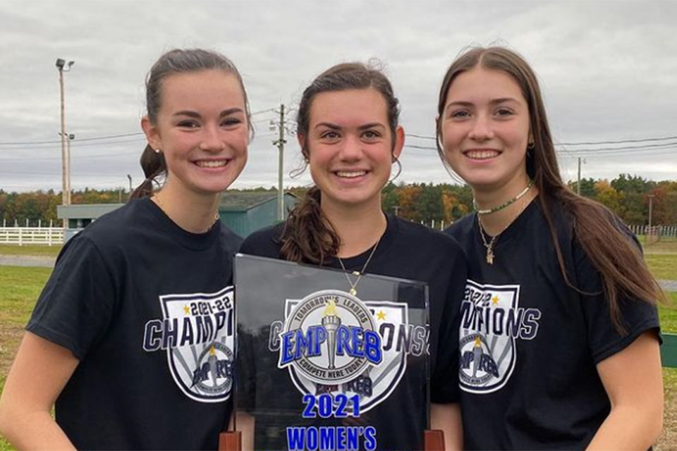 The Collins sisters hold up the Empire 8 Championship trophy.