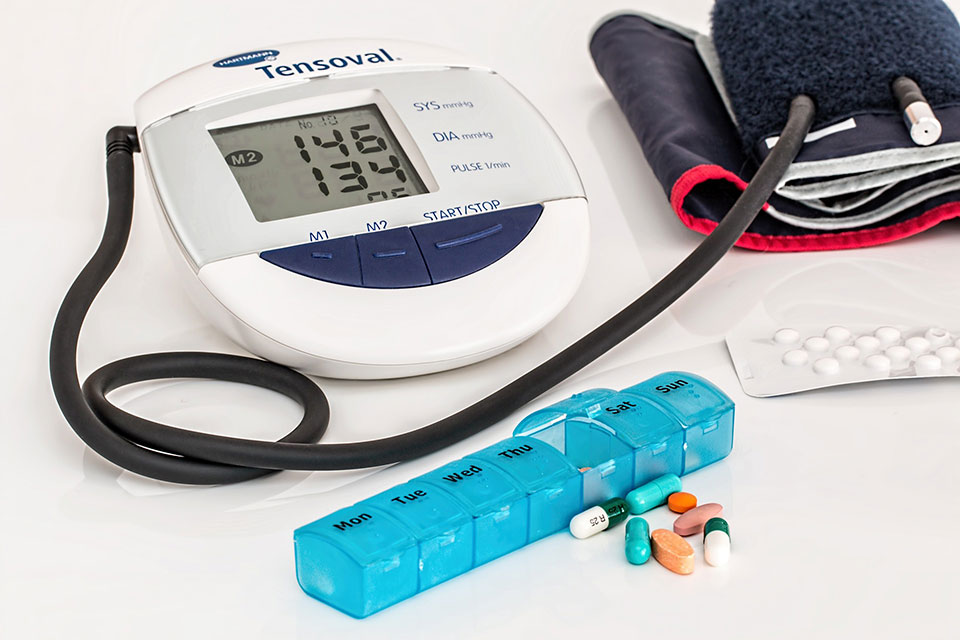 A blood pressure cuff, medicine box, and pills.