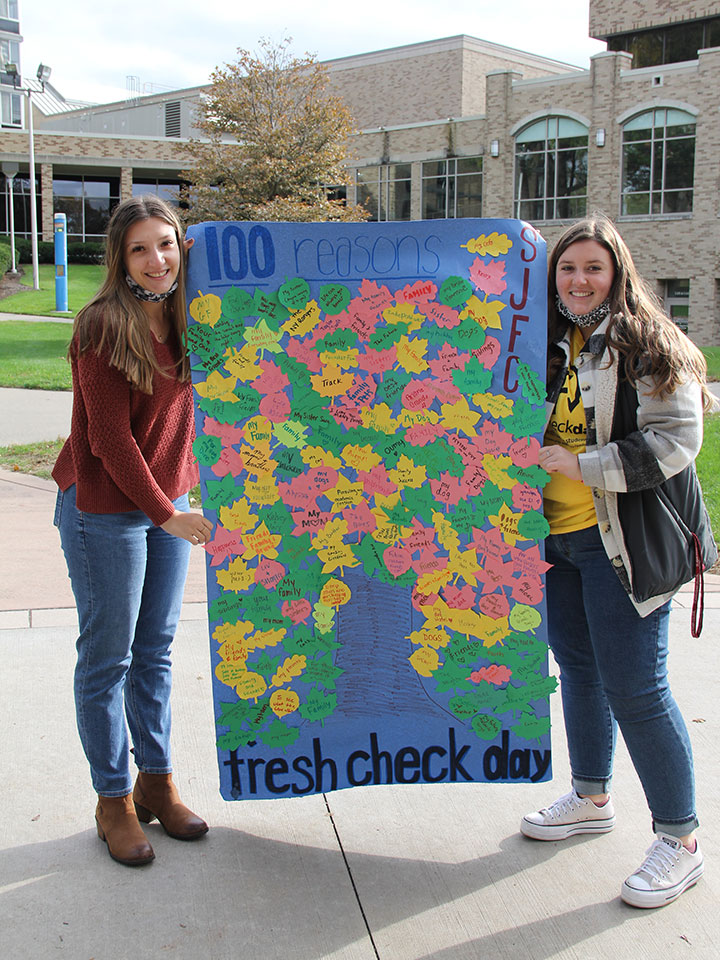The Pyschology Club holds up a Tree of Reasons poster.