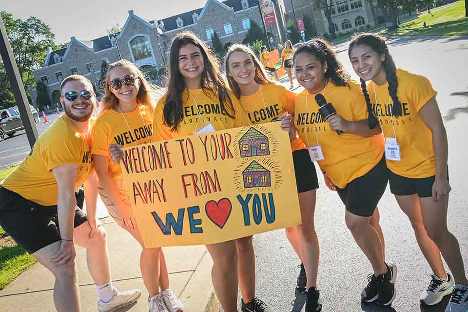 Members of Fisher's Orientation Team hold a sign to welcome new students to campus in the Welcome Parade.