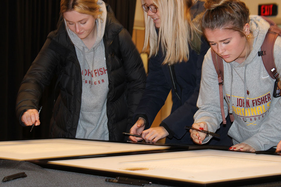 Two students sign the Fisher Creed.