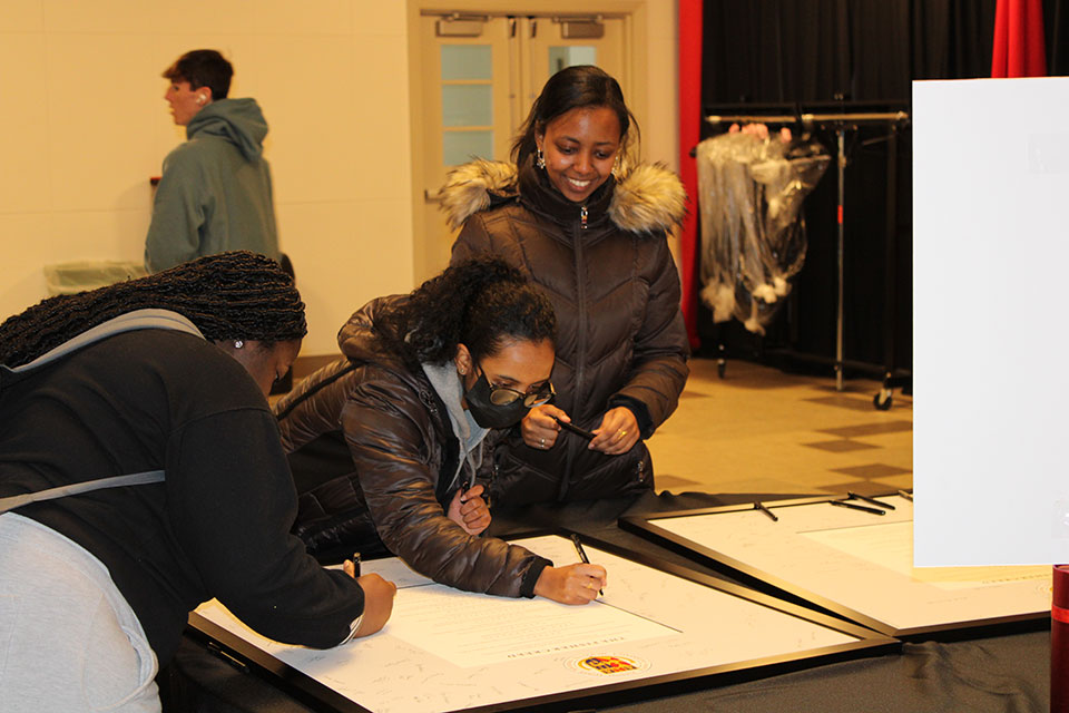 Three students sign the Fisher Creed.