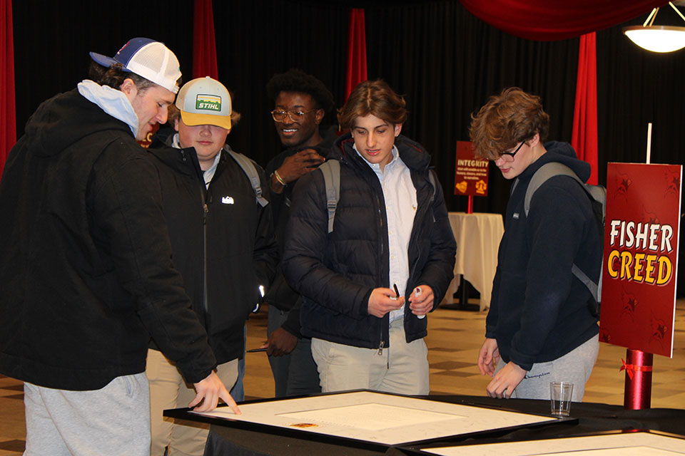 A group of students sign the Fisher Creed.
