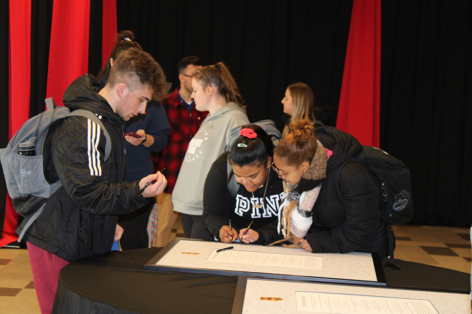 Students gather to sign the Fisher Creed.