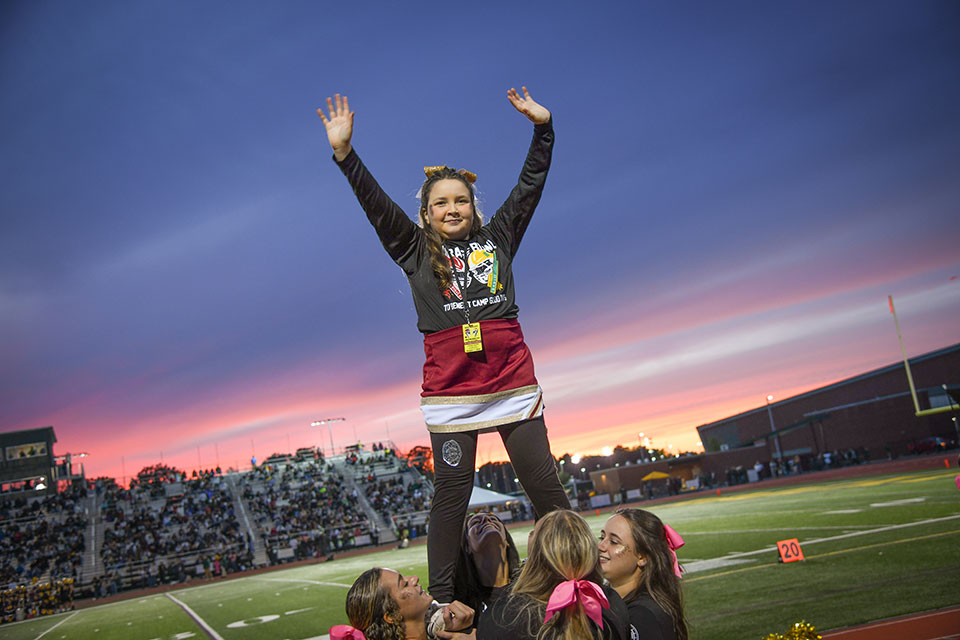 Fisher cheerleaders lift honorary cheerleader Karleigh Sackett in a mount.