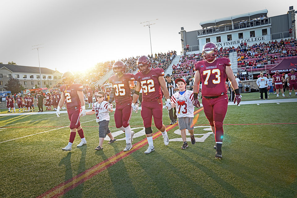 Fisher football players walk out to the coin toss with their honorary coaches.