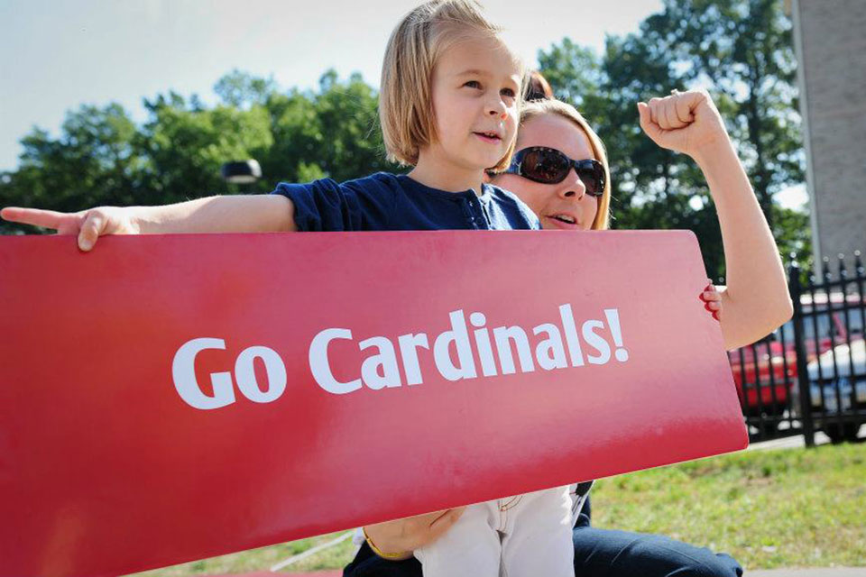 An alumna and her daughter hold up a sign cheering on the Cardinal football team.