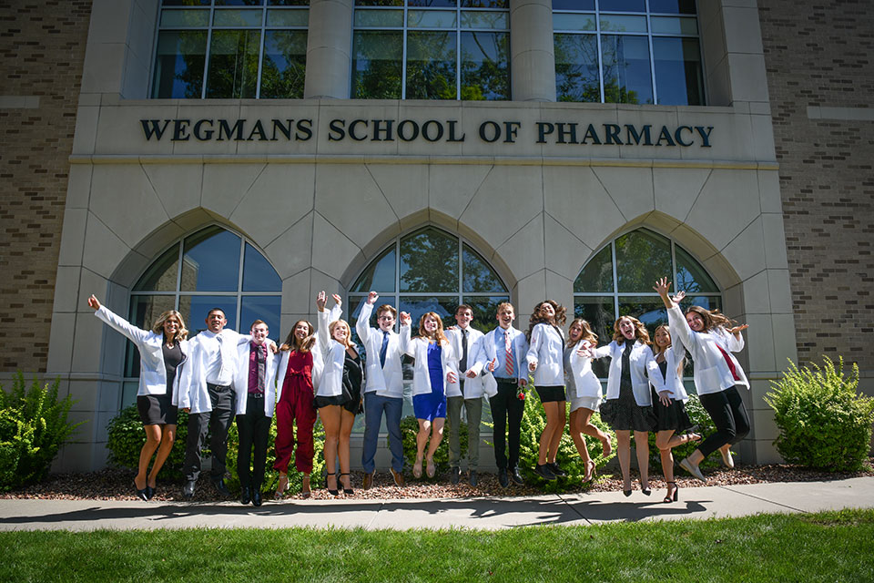 Students celebrate in their white coats outside of the Wegmans School of Pharmacy.