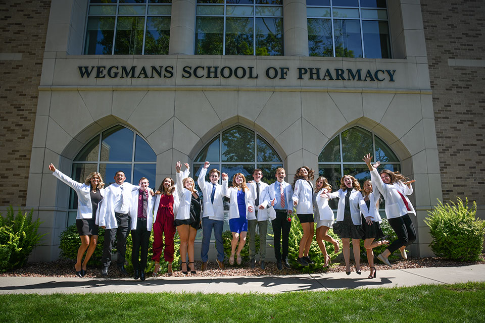 Students celebrate in their white coats outside of the Wegmans School of Pharmacy.