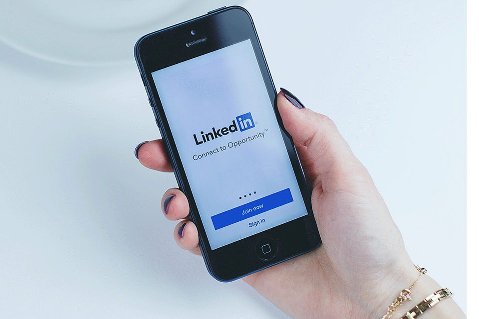 A person holds a phone with the LinkedIn App.