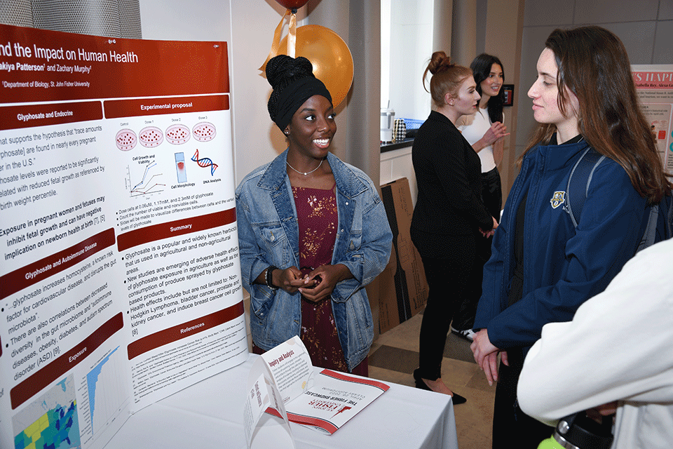 A student shares research with an attendee at the 2023 Fisher Showcase.