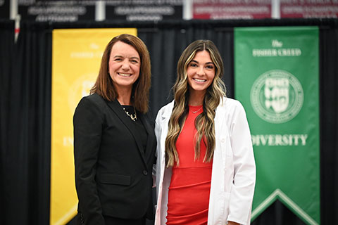 Dean Christine Birnie poses with a student in a white coat.