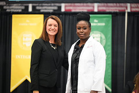 Dean Christine Birnie poses with a student in a white coat.