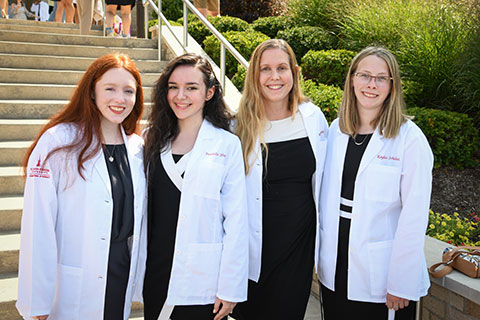 First year pharmacy students celebrate in their white coats.