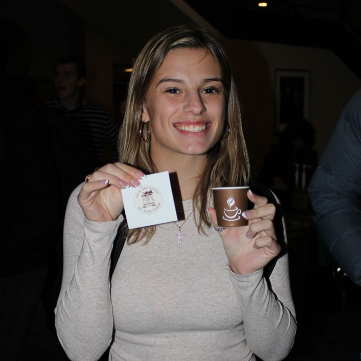 A student holds up a coffee sample from Luigi's.