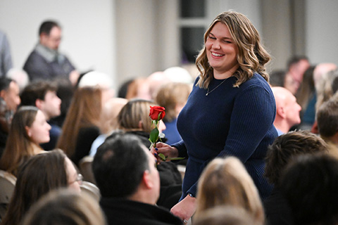 A student walks through the crowd with a rose during the nursing pinning ceremony.