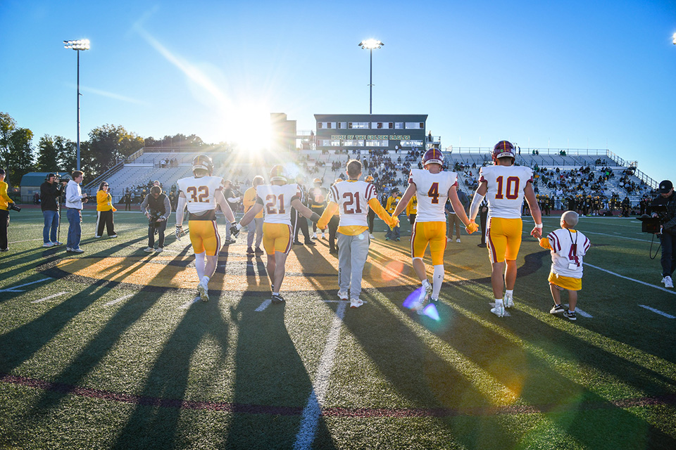 Fisher players with Camp Good Days coaches holding hands.
