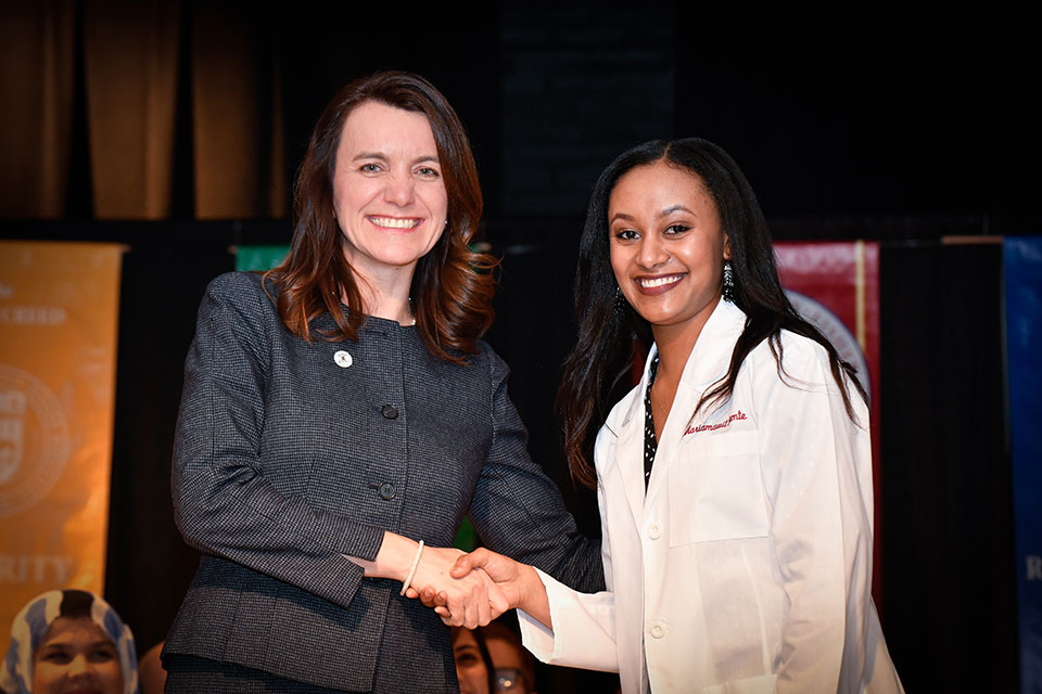 Dr. Christine Birnie gives a white coat to a member of the Class of 2022.