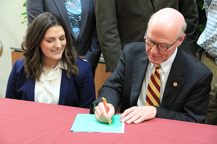 Gabriella Kielbasinski ’19 watches as President Rooney signs a letter endorsing carbon pricing for its economy-wide approach to lowering greenhouse gas emissions that cause climate change.
