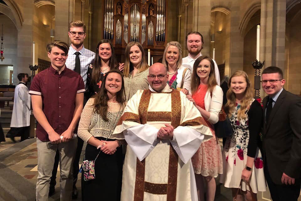 Fisher students surround Jnathan Schott ’02 after a Catholic Mass where he was ordained a permanent deacon.