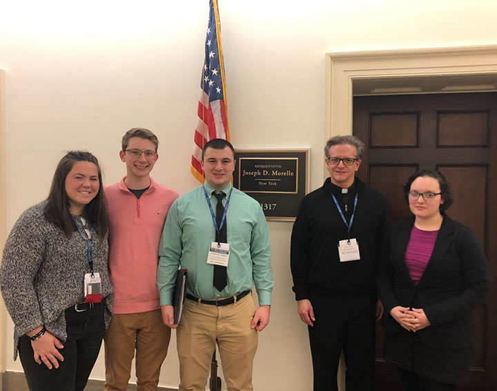 Fisher students with Fr. Kevin Mannara outside of Congressman Joe Morelle's office.
