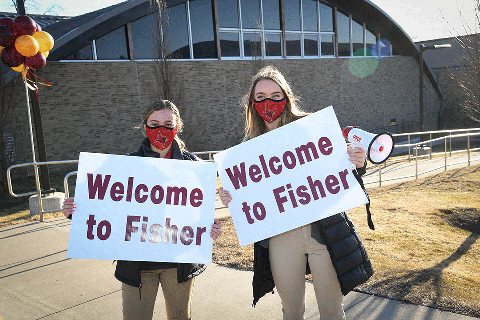Two students hold signs that read Welcome to Fisher. 