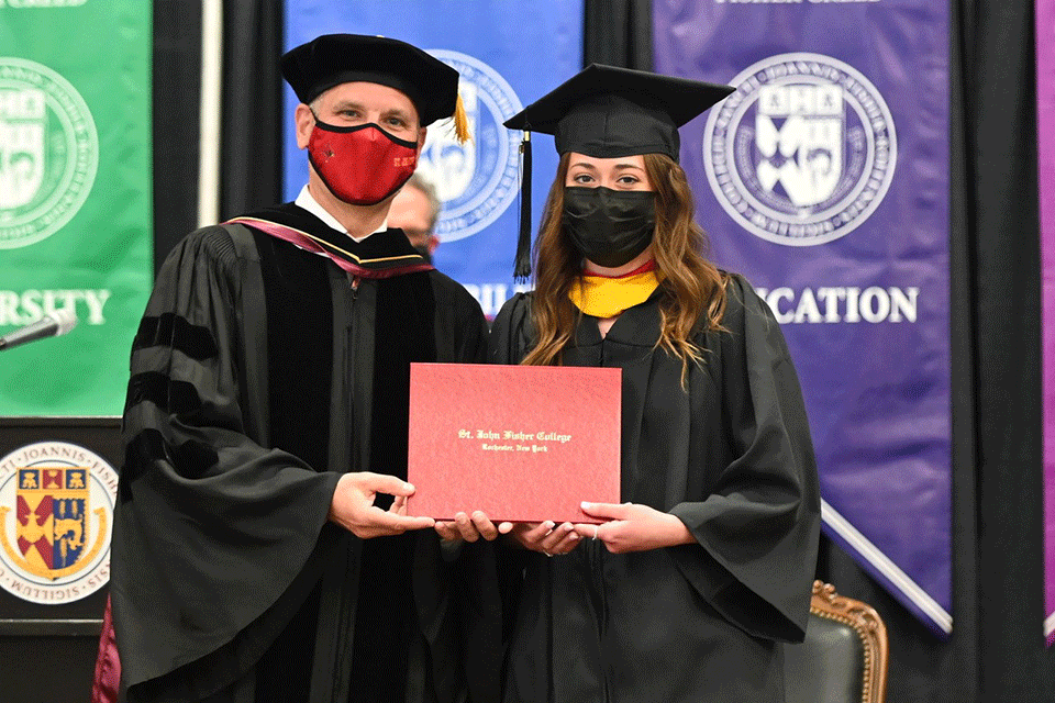 A student-athlete receives her diploma during a special Commencement ceremony for in-season athletes.