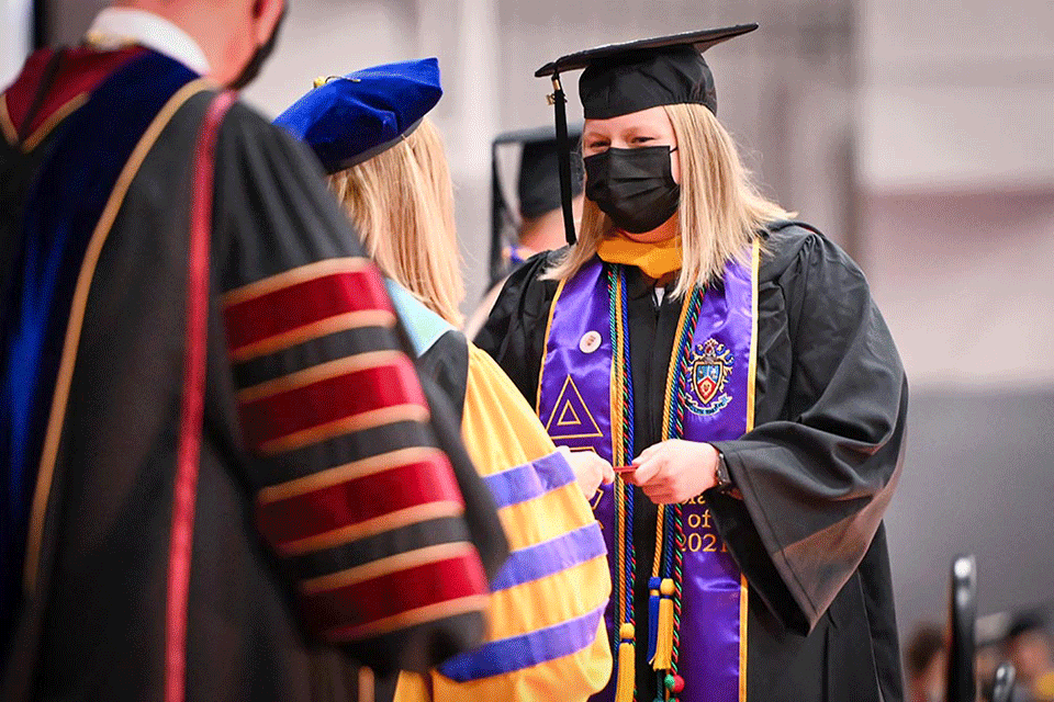 New graduate Emma Pyrak receives her diploma during the School of Business Commencement ceremony.