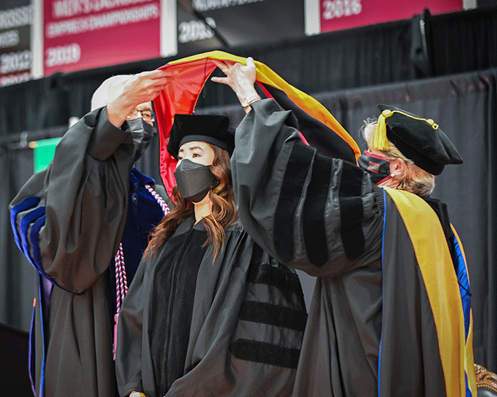 A doctoral candidate is hooded during the School of Nursing ceremony.