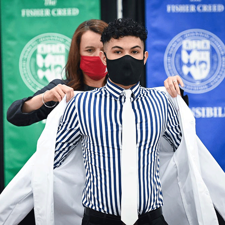 A pharmacy students recieves his white coat from Dean Christine Birnie.