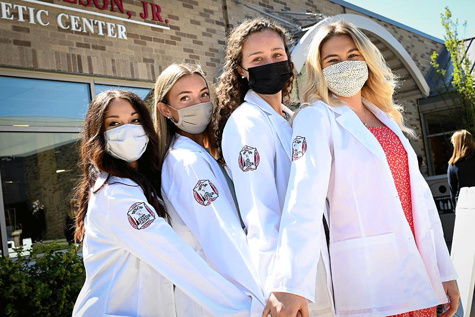 Members of the Class of 2024 pose in their white coats.