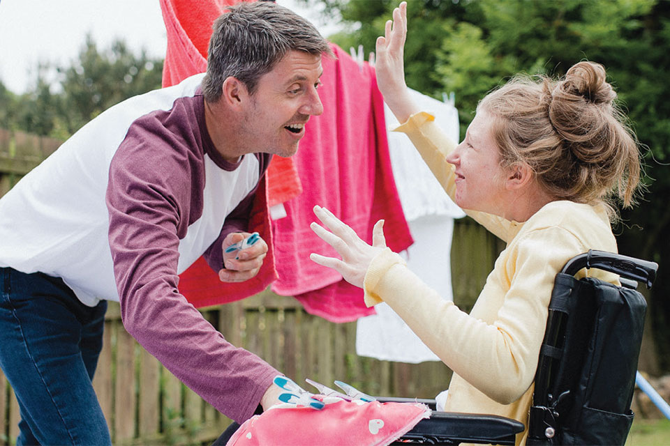 A man greets a woman who is using a wheelchair.