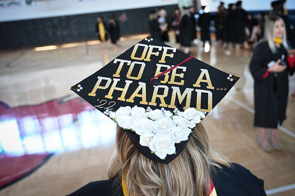 A Class of 2022 wears a mortar board that reads, Off to be a Pharm.D.!