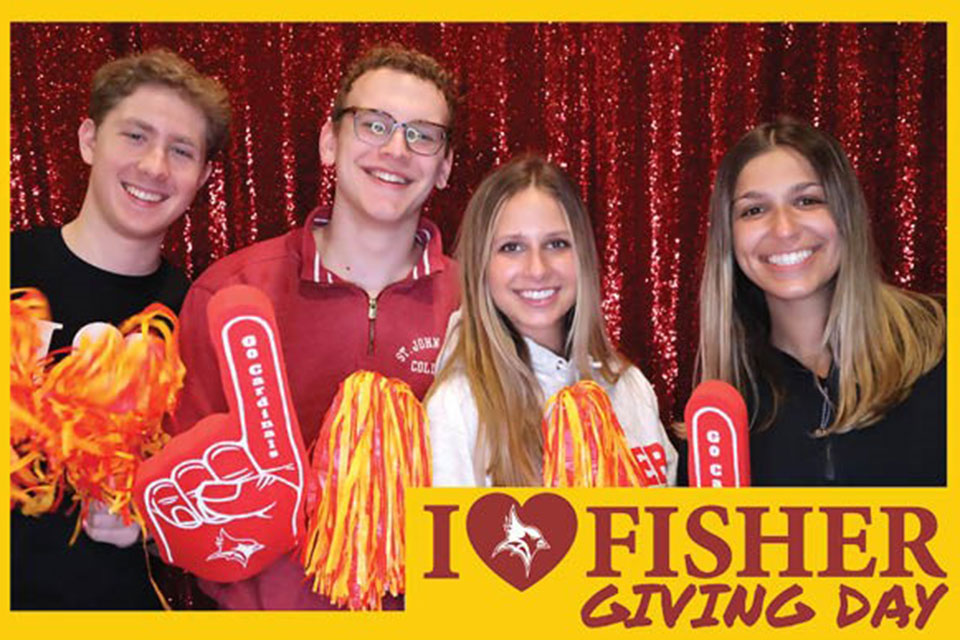 Four students pose in the I Heart Fisher Giving Day photo booth.