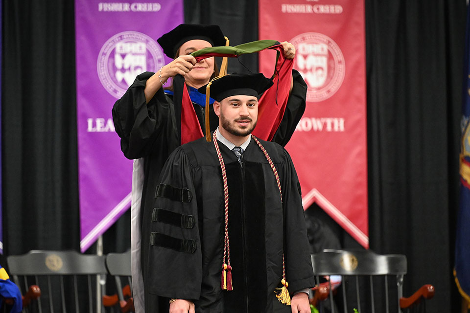 A pharmacy graduate is hooded during the Commencement ceremony.