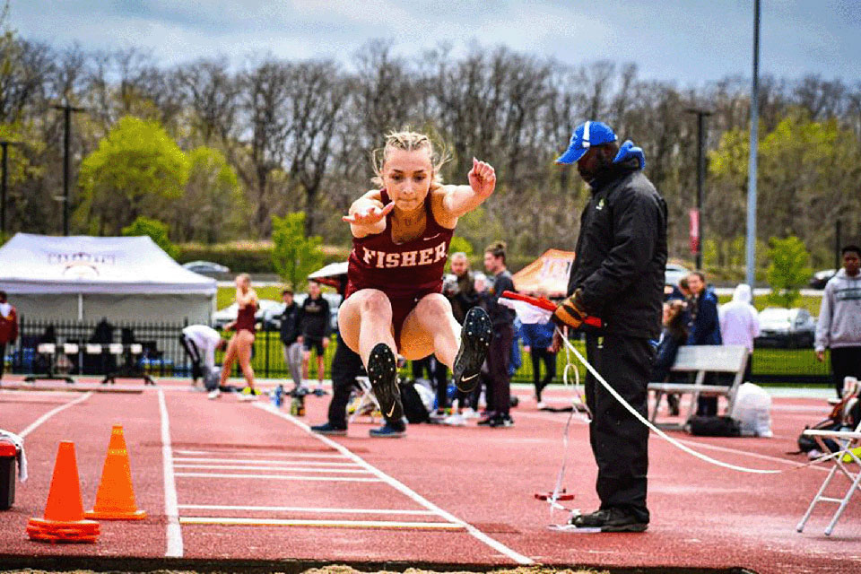 A Fisher student-athlete competes in the long jump event.