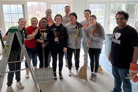 A group of volunteers pose with gardening equipment.